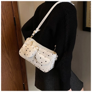 Detailed view of a white polka dot shoulder bag with a small heart-shaped coin purse attachment