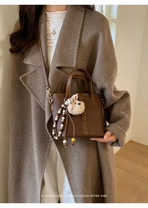 Detail of dark brown lychee leather bucket bag with retro beaded chain and charm