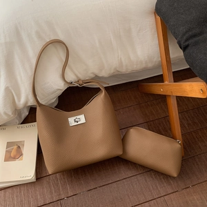 Close-up of pebble leather texture and metal turn-lock on the tan shoulder bag set