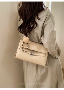 Detail of beige retro crossbody bag with silver twist lock and cute teddy bear charm