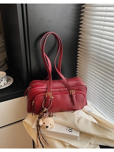 Detail of burgundy leather bowling bag with cute dog pendant and metal zippers