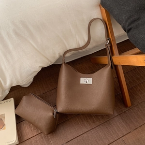 Detailed macro of brown lychee grain leather tote bag with silver metal twist-lock