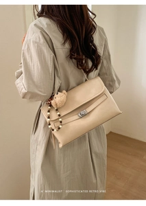 Detail of beige minimalist crossbody bag with metal twist lock and cute bear charm