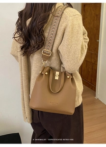 Detail of brown leather bucket bag with colorful ethnic style woven shoulder strap