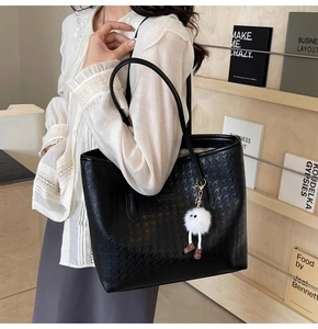 Detail of black tote bag with star embossing and plush charm on a shoulder strap
