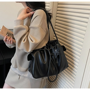Detail of black large capacity leather tote bag with drawstring closure and star charm
