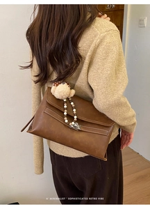 Close-up of retro brown leather shoulder bag with silver twist lock and cute plush charm