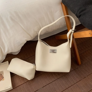 Close-up of beige lychee grain leather underarm bag with silver lock and small pouch