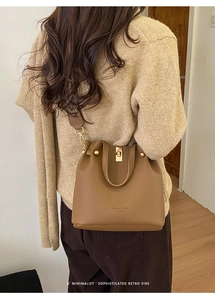 Close-up of brown lychee texture leather bucket bag with gold hardware and logo detail