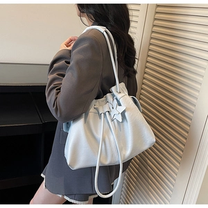 Chic light blue pleated tote bag with star charm worn by a model in a grey blazer