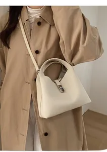 Detail view of the cream leather bucket bag showing the clasp and shoulder strap texture