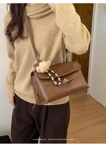 Close-up of vintage brown leather crossbody bag with silver lock and bear pendant