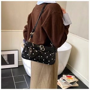 Close-up of heart-shaped pocket and gold clasp on black polka dot crossbody bag