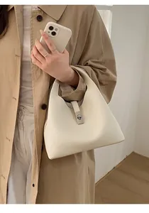 Close-up of cream white leather bucket bag featuring a silver metal clasp and lychee texture