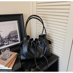 Detail of a large black soft PU leather tote bag with drawstring closure and shoulder straps