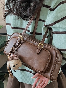 Vintage dark brown bowling bag with plush dog charm shown on shoulder for daily commute