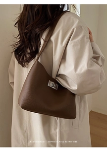 Close-up detail of dark brown lychee pattern leather shoulder bag with silver turn-lock