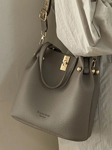 Taupe pebbled leather bucket bag with gold hardware and ethnic style wide woven strap