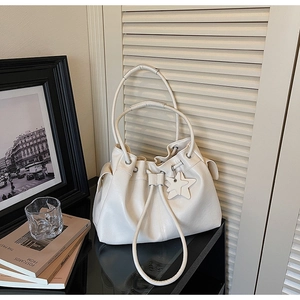 Detail view of the drawstring bucket tote bag with star charm on a modern table