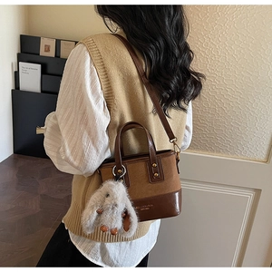 Détail d'un sac seau vintage marron foncé avec un charmant lapin en peluche et bandoulière