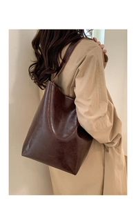 Detail of the vintage dark brown wax leather bucket bag with embossed logo on the bottom