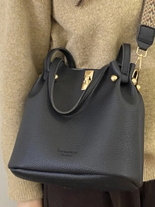 Large black pebbled leather bucket bag with a stylish geometric woven shoulder strap