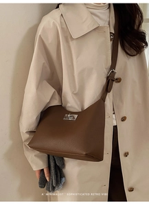 Close-up of a brown leather shoulder bag with a silver square metal twist lock clasp