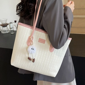Elegant cream tote bag with pink trim and plush charm in a chic cafe setting