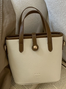 Minimalist cream and brown leather bucket bag with large capacity for daily commuting