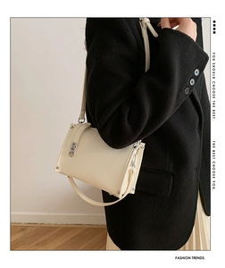 Detailed view of white litchi leather texture and silver buckle on crossbody bag