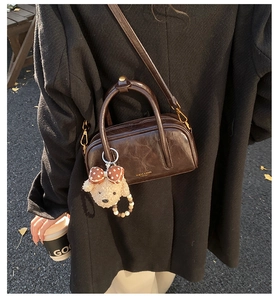 Détail du sac bowling en similicuir marron avec une breloque d'ours en peluche mignon