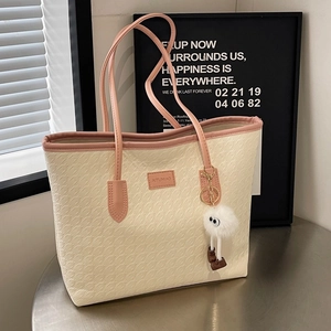 Fashionable beige houndstooth tote bag with pink leather handles and plush monster charm