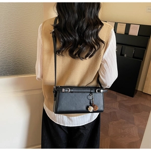 Back view of black leather crossbody bag with silver buckle and plush charms