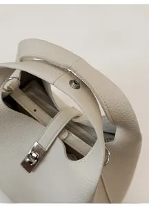 Close-up of wide leather handle and iconic metal buckle on cream bucket bag