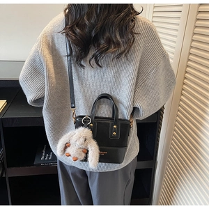 Détail du sac seau en cuir noir avec rivets dorés et joli charm lapin en peluche doux