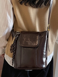 Brown glossy bucket bag with gold lettering and decorative silk scarf for stylish daily use