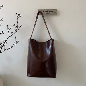 Close-up of vintage dark brown wax leather bucket bag showing texture and logo
