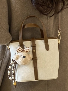 Chic cream leather bucket bag with brown handles and cute bear charm for women