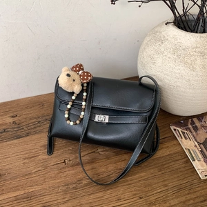 Detail of black leather flap bag featuring white stitching and a silver turn-lock closure