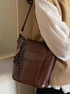 Fashionable dark brown polished leather bucket bag with gold logo for casual commuting