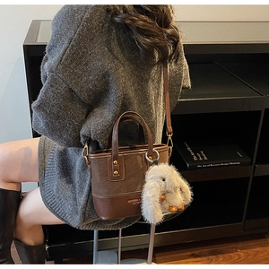 Détail du sac cabas vintage en similicuir marron foncé avec un joli pendentif lapin en fourrure