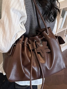 Deep brown vintage leather tote bag with star charm worn by a model in a cozy study