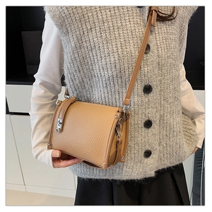 Detail of light brown crossbody bag with silver twist lock on a grey knit vest outfit