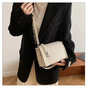 Detail of off-white lychee grain leather crossbody bag with silver twist lock and studs