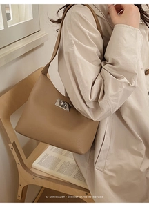 Detailed close-up of brown litchi pattern leather bag with polished metal twist lock