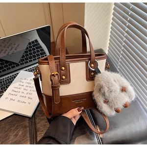 Détail du sac seau bicolore avec boucles en bronze et breloque lapin en peluche