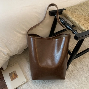 Detailed view of deep brown vintage bucket bag on white carpet with minimal aesthetic