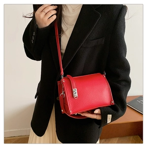 Detail of red lychee pattern leather shoulder bag with silver clasp and adjustable strap