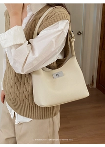 Close-up of beige lychee grain leather bucket bag with silver metal turn-lock closure