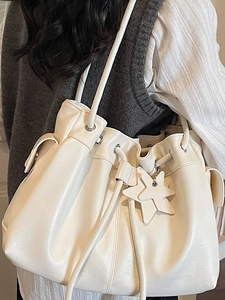 Chic cream white drawstring bucket bag with star pendant shown in a stylish side view
